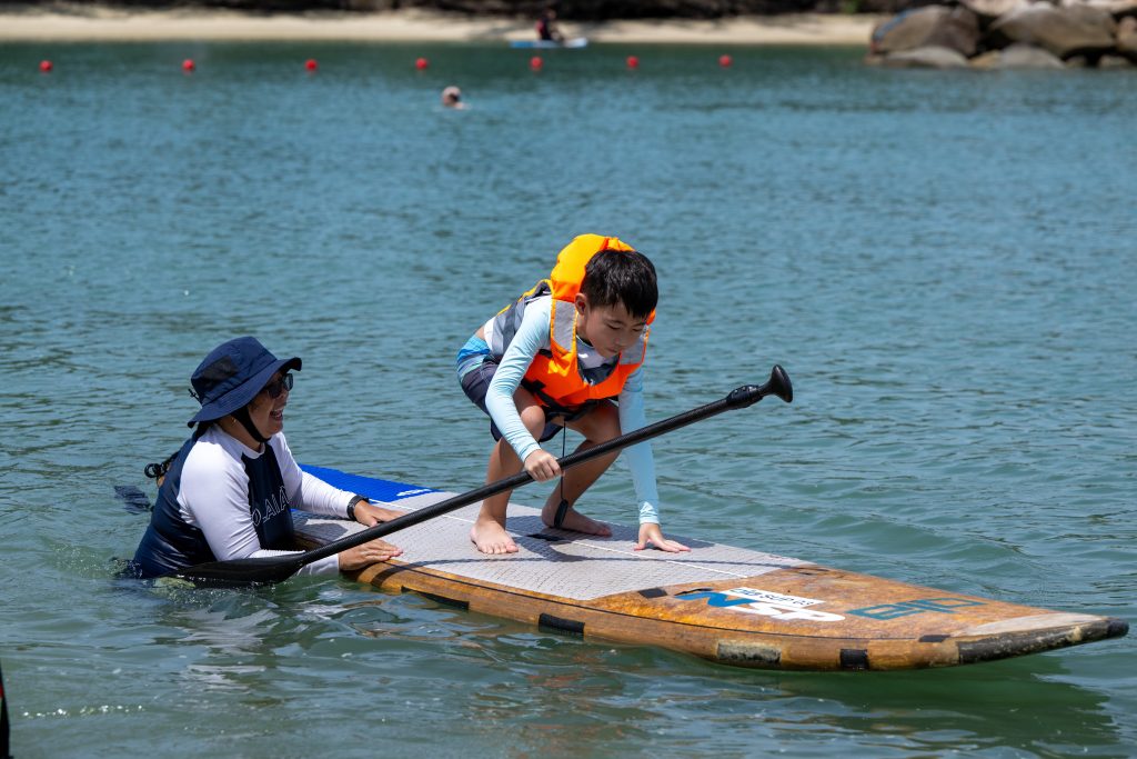 Grace Mission co-founder, Mrs Grace Choo, guiding a young
boy on how to balance standing up on the SUP.