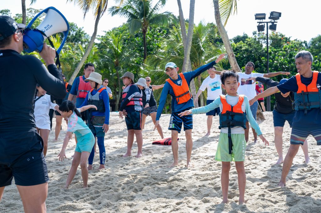 Youths with autism and their families doing a guided warm up
led by Elevate Performance Coaching before they head off to
SUP at sea.